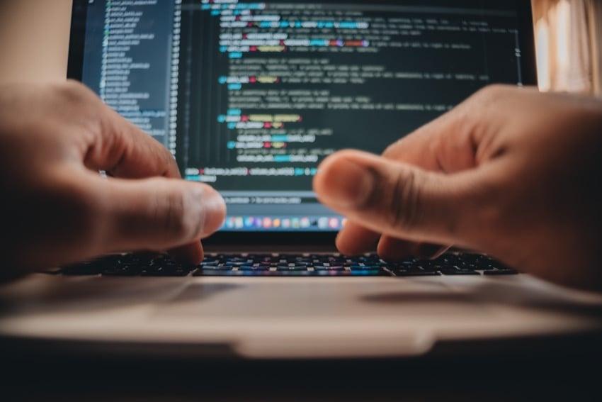 Hands typing programming on laptop